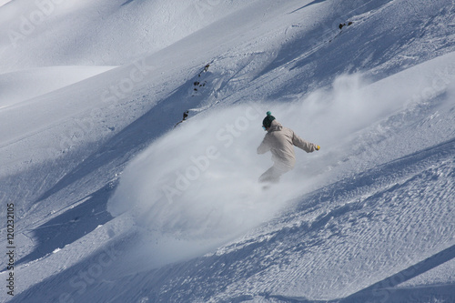 Obraz na plátně Snowboarder Makes a Powder Turn While Doing Extreme Snowboarding in the Mountain