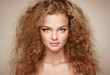 Fashion portrait of young beautiful woman with jewelry and elegant hairstyle. Redhead girl with long curly hair. Perfect make-up