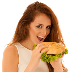 Wall Mural - Unhealthy meal - happy young woman eats hamburger isolated over