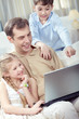© pressmaster - Father with his children using laptop at home