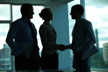 Three Business People Greeting In Office In The Dark
