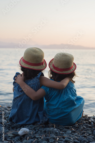 Fotografia petites filles bras dessus bras dessous assises au bord de la mer