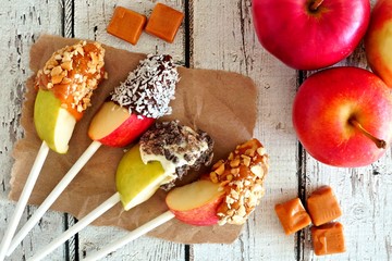 Aufkleber - Autumn apples slices dipped with chocolate and caramel, scene on a rustic white wood