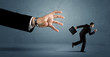 © ra2 studio - Business man running away from a huge hand concept