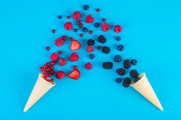 Wall Mural - Wild berries in two wafer cups, wafer cones with different berries on a blue background.