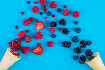 Wild berries in two wafer cups, wafer cones with different berries on a blue background.