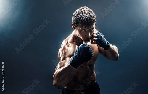 Cuadros en Lienzo Muscular kickbox or muay thai fighter punching in smoke.