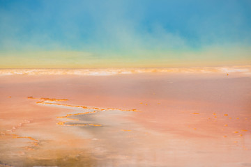 Rising blue steam and mist from Grand Prismatic hot spring in Midway Geyser basin at Yellowstone National Park with red bacterial patterns