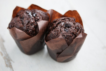 Two tasty chocolate muffins on wooden table