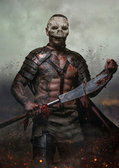 Male in the skull mask holds sword in the dust batterfield backg