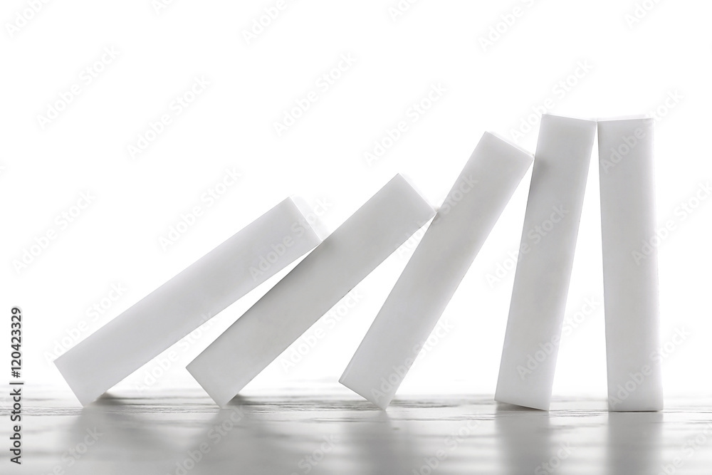 Line of dominoes falling on light wooden background