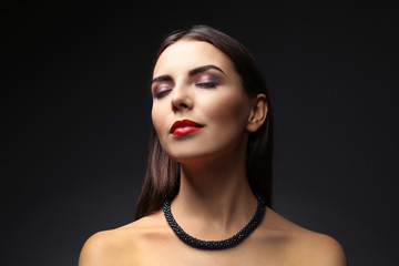 Portrait of beautiful young woman model with bright makeup on dark background