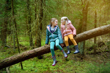 Two funny little sisters having fun during forest hike