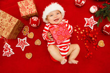 Baby First Christmas. Beautiful Little Baby Celebrates Christmas. New Year's Holidays. Baby With Santa Hat With Gift. Santa Baby.

