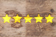 Five yellow ranking stars on wooden background