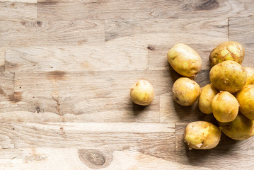 Wall Mural - beautiful pile small rounded whole organic potatoes with the peel on an old oak cutting board seen from above