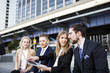 © Astrakan Images - Businesswoman showing laptop to colleagues against buildings in city