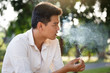 © weerajata - Man smoking, he lifestyle and blurred tree Background