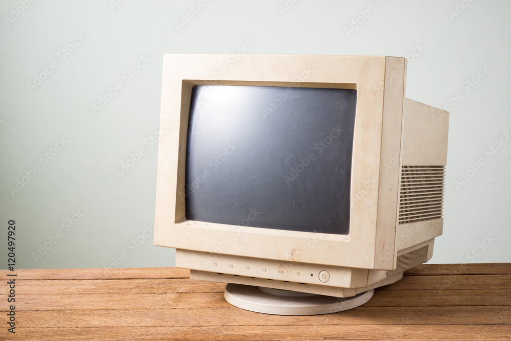 old and obsolete computer monitor on old wood table with concrete wall background