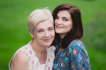 Mother and adult daughter in a green park posing together