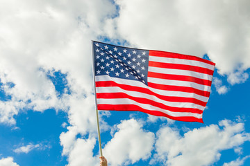 USA flag on a flagpole with clouds on background