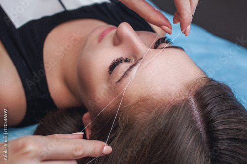 Fotografering Master corrects makeup, gives shape and thread plucks eyebrows in a beauty salon