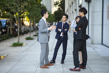 Canvas Print - Four businessmen who are the stand talking in the office district