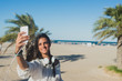© ADDICTIVE STOCK - Happy brunette makes selfie on the beach