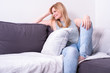 © Jürgen Hüls - beautiful blonde woman is smiling and relaxing on gray couch