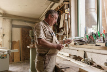 Master Carpenter At His Workbench Reading Orders