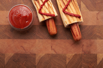 two French hot dogs and sauce on a wooden table