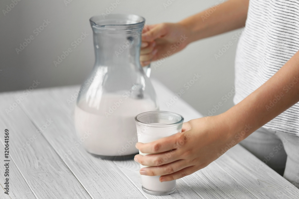 Female hands with milk in jug and glass
