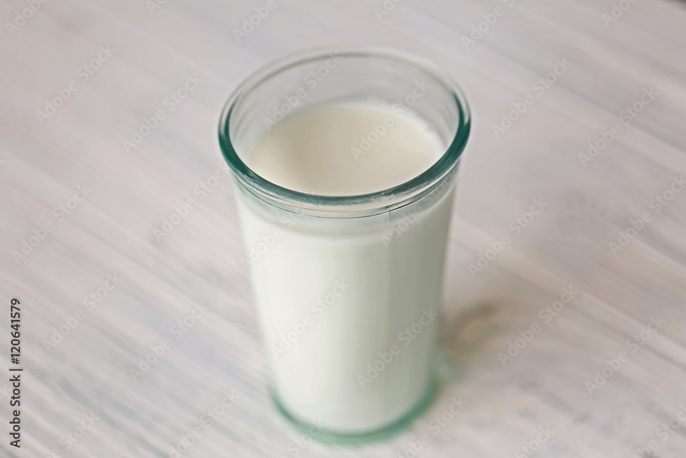 Glass of fresh milk on light blurred background