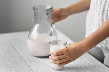 Wall Mural - Female hands with milk in jug and glass