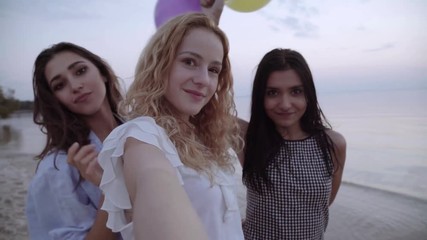 mixed race friends making selfie. three beautiful young women making selfie at sunset on a beach.