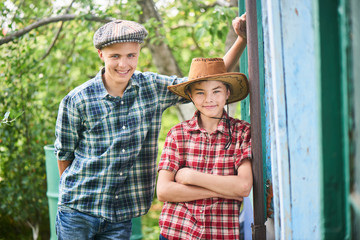 Portrait of two brothers are smiling leaning on the wall of a building on the farm