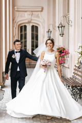 Wall Mural - Beautiful bride and groom walking together and laughting outdoor