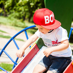 Little boy playing outdoors in park laughing ride on the swing