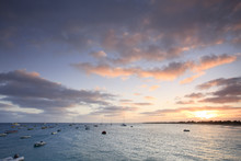 Scenic View Of Boats In Ocean At Sunset