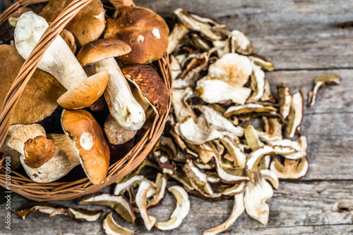 Cuadros en Lienzo Fresh boletus mushrooms in a basket and dry mushrooms on wooden