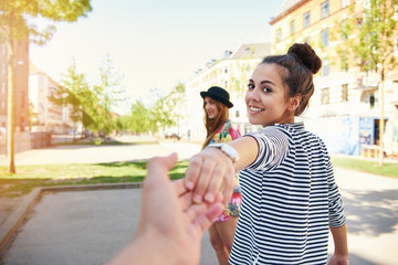 Pretty young woman pulling a man along