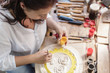 © Kzenon Premium - Woman in woodcarving studio painting wooden ornament