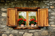 Alpine Window With Shutters And Red Flowers