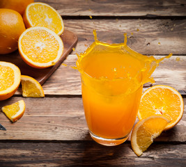 Wall Mural - glass of splashing orange juice on wood