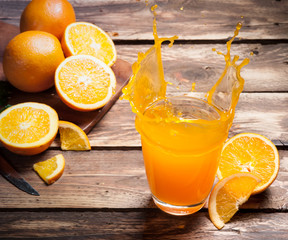Wall Mural - glass of splashing orange juice on wood