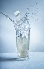 Poster - Ice cubes with water splash in glasses on blue background