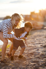 Wall Mural - Beautiful woman with a child of four years playing on the beach near the sea