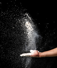 Hand and flour on black background