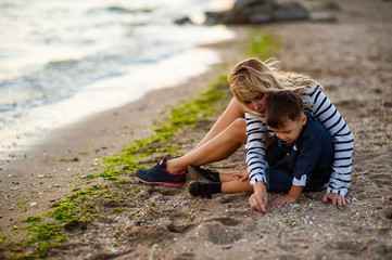 Wall Mural - Beautiful woman with a child of four years playing on the beach near the sea