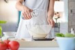 Woman adding water to flour in a bowl.